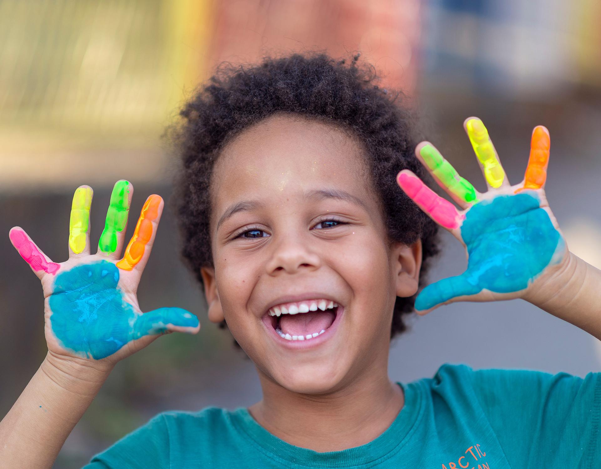 young kid smiling with painted hands