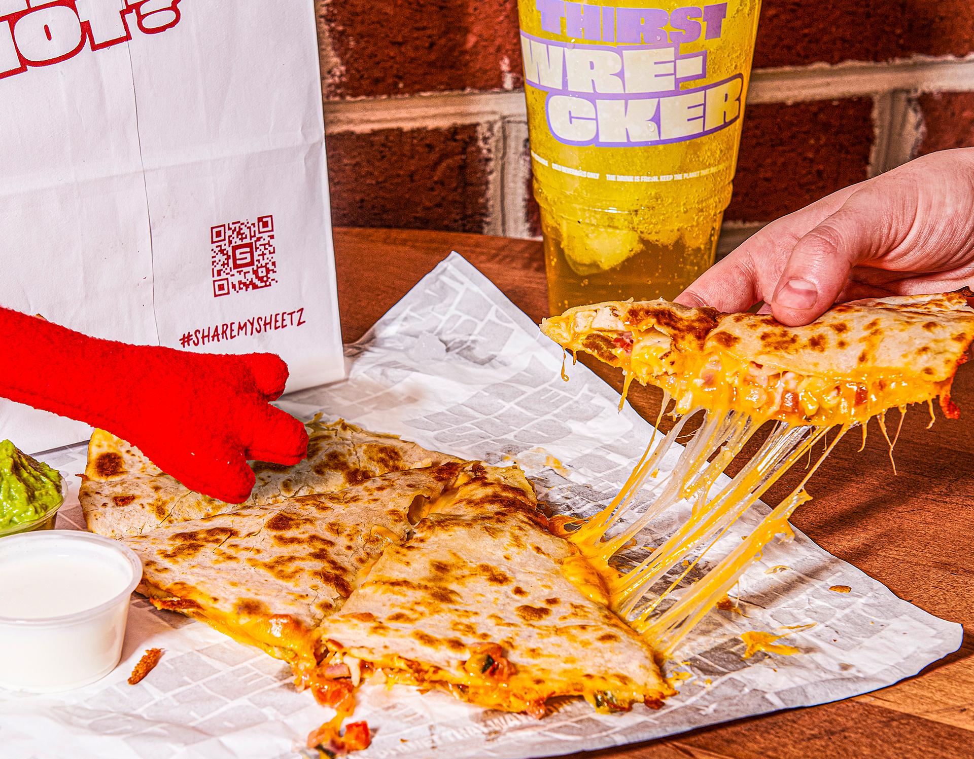 Quesadilla and soda on top of a table with a brick wall in the background