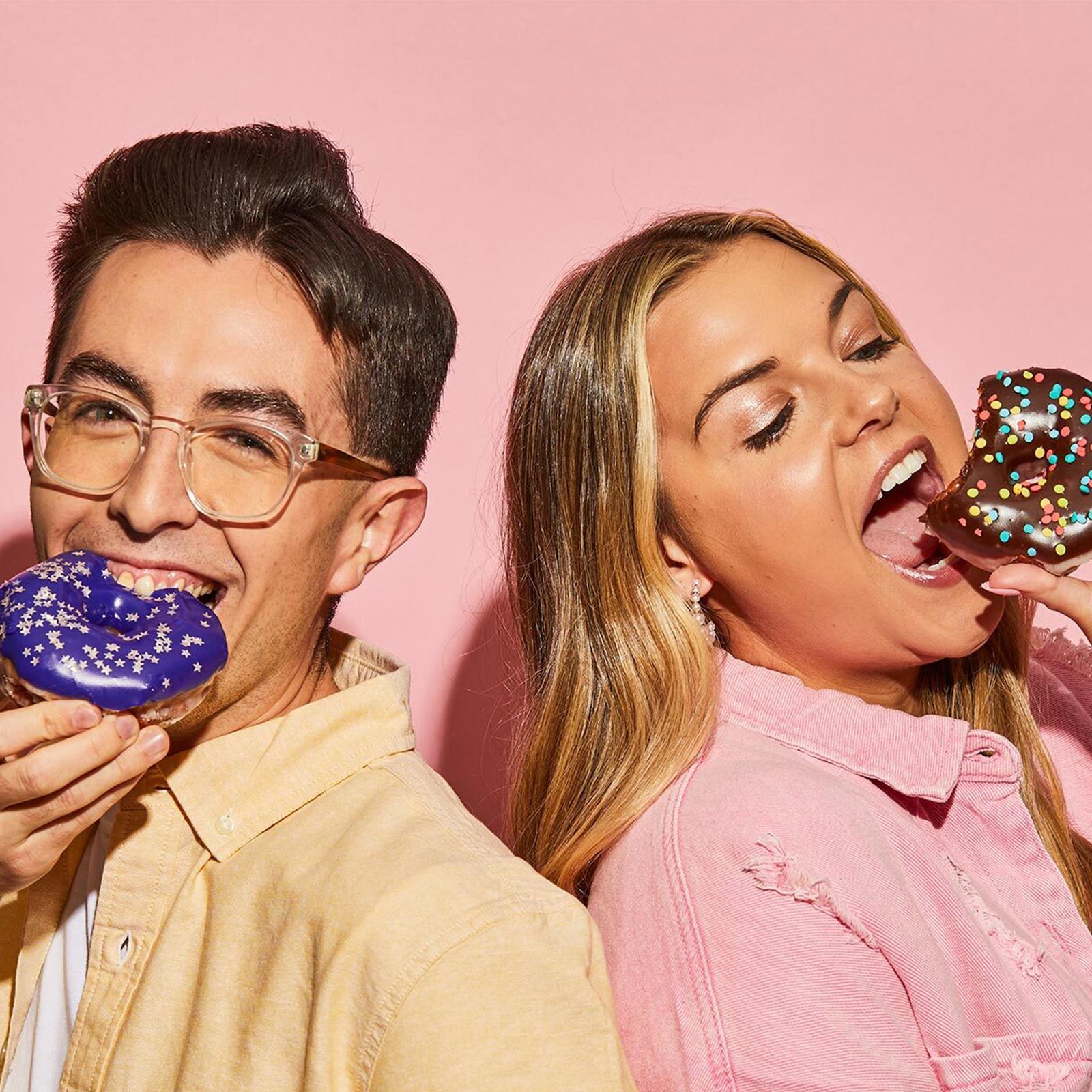 two sheetz employees biting into donuts