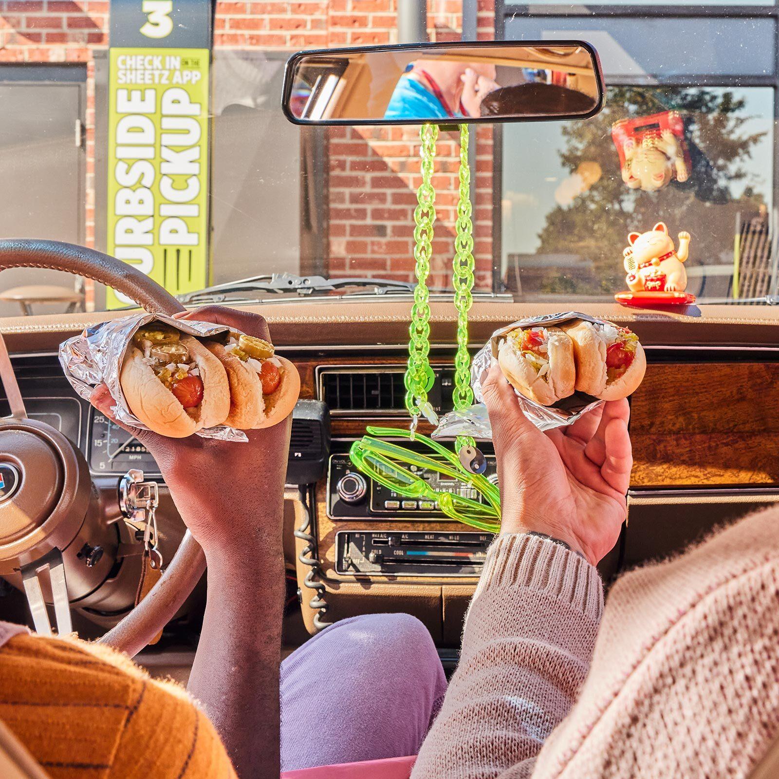 two males in a car holding hot dogs