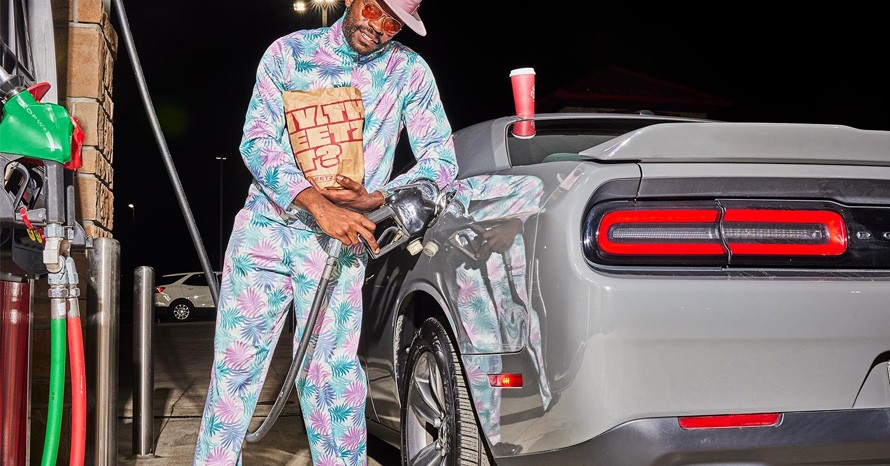 man filling up his car with gas with some sheetz food in-hand